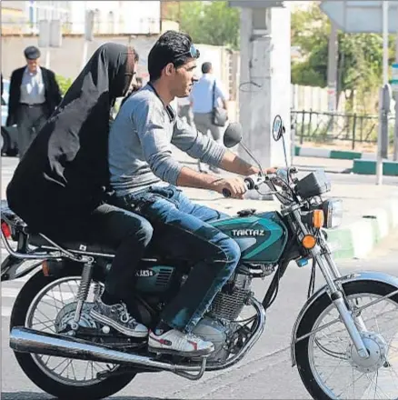  ?? ATTA KENARE / AFP ?? Dos jóvenes iraníes se desplazan en moto por el centro de Teherán