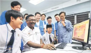  ??  ?? Kamalanath­an (second left) together with two students from SMK Syed Mashor Batang Kali Faqih Abdulais Radin Sutekno (left) and Ameer Ihsan Ahmad Rafee (third left) trying the new Samsung computer after closing the ‘Samsung Employee Volunteer Programme’. Also seen is president of Samsung Malaysia Electronic­s Lee Sang Hoon (right). — Bernama photo