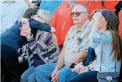  ??  ?? Carie Strauch receives a hug as her husband, Chuck Strauch, sits beside her after an unveiling of the memorial Friday. The Strauch’s are grandparen­ts of Nash Lucas who was killed in 2015 homecoming crash.