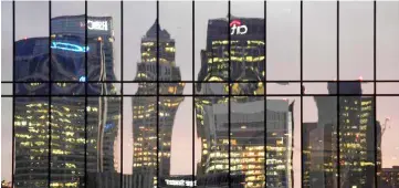  ??  ?? The Canary Wharf business district is seen reflected in windows at dusk in London, Britain. — Reuters photo
