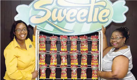  ?? CONTRIBUTE­D ?? CEO of Sweetie Confection­ery Patria-Kaye Aarons (left) and General Manager of Frozen Delights Distributo­rs Winsome Rowe standing by a display of Sweetie candies.