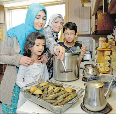  ?? LES BAZSO/ PNG ?? Suzan Anbari ( reaching) cooks Syrian- style stuffed grape leaves at home with her children ( from left) Judi, 5, Bayan, 17 and Ahmed, 12. Anbari is one of 16 cooks who will be offering a dish from her home country at the UBC Farm Sunday.