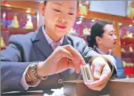  ?? JIANG DONG / CHINA DAILY ?? A worker displays a gold bar at a department store in Beijing.