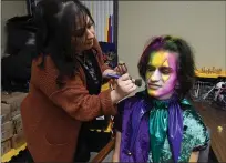  ?? ?? Makeup artist Angie Fletes puts some finishing touches on Jester Dominiq Dluna, of Vallejo, as he prepares for the Mardi Gras festival at Six Flags Discovery Kingdom in Vallejo on Saturday.
