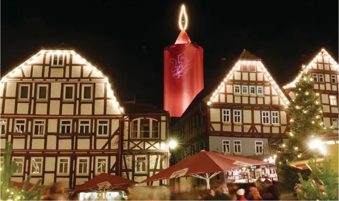  ??  ?? SCHLITZ: Timber-framed buildings are illuminate­d in front of a tower setup as a giant candle in Schlitz, Germany on Saturday. The 36 meter (118 ft) high tower is the main attraction of the Christmas market in the town of Schlitz in the German state of...