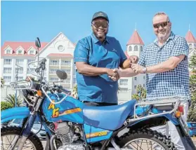  ?? ?? SAFETY SUPPORT: Boardwalk general manager Tati Tsunke hands over a Yamaha motorbike to Beachfront Safety Sector chair Shaun Tappan