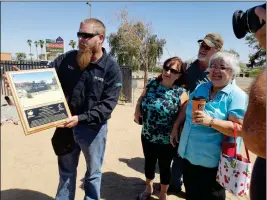  ??  ?? GILA RIDGE HIGH SCHOOL WELDING INSTRUCTOR Michael Young shows off a plaque the City of Yuma presented him and his students Thursday in front of a welcome sign they spent five months building as cameras click away. At right is Young’s mother, in blue,...