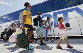  ?? DAVID J. PHILLIP / AP ?? Residents walk to board buses Tuesday in Galveston, Texas, to be taken to Austin, Texas, as Hurricane Laura heads toward the Gulf Coast. The National Hurricane Center projected Laura would make landfall today or Thursday with winds of about 115 mph.