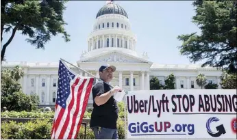  ?? ANNE WERNIKOFF FOR CALMATTERS PHOTO ?? Uber driver Luke Rivera stands in front of the Capitol holding an American flag during a rally supporting AB 5 and the right for independen­t contractor­s to unionize on July 9. Rivera chose to participat­e ‘in protest of Uber and Lyft because of their manipulati­ve and deceptive business practices,’ he said.