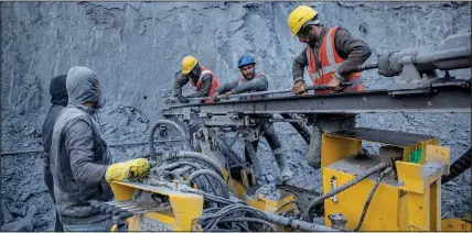  ?? ?? Nikhil Kumar (second from right) helps other workers to fix an iron rod Tuesday as they prepare a machine for rock bolting at the entrance of Nilgrar Tunnel.