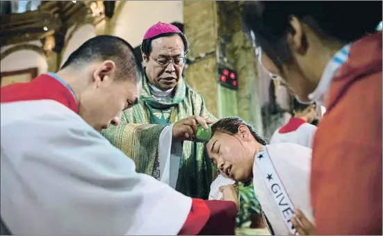  ?? NICOLAS ASFOURI / AFP ?? Dotze milions de catòlics El bisbe Joseph Li Shan batejant ahir una dona durant la missa a la catedral Sud de Pequín. Es calcula que a la Xina hi viuen uns 12 milions de catòlics