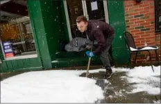  ?? KRISTOPHER RADDER /THE BRATTLEBOR­O REFORMER VIA AP ?? Mikey Reynolds, an employee at The Works on Main Street in Brattlebor­o, Vt., shovels the sidewalk in front of the restaurant as a person who is facing homelessne­ss sleeps in a door entryway while seeking refuge from the snow storm on Saturday, March 23, 2024.