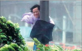  ?? TYRONE SIU/ REUTERS ?? A man holds onto a lamppost against strong wind as Typhoon Hato hits Hong Kong on Wednesday. The strongest typhoon this year hit coastal areas with fierce winds and waves.