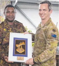  ??  ?? Major Benjamin Jankalns is presented memorabili­a by Captain Derek Levi from the PNG during the farewell parade.