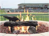  ?? MATT DEVRIES, GREAT LAKES LOONS ?? Fans of the Great Lake Loons in Midland, Mich., can keep warm at outfield fire pits.