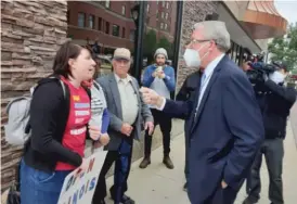  ?? NEAL EARLEY/SUN-TIMES ?? House Republican Leader Jim Durkin confronts protester Brittany Emel about her sign comparing Gov. J.B. Pritzker to Adolf Hitler on Wednesday outside the Bank of Springfiel­d Center.