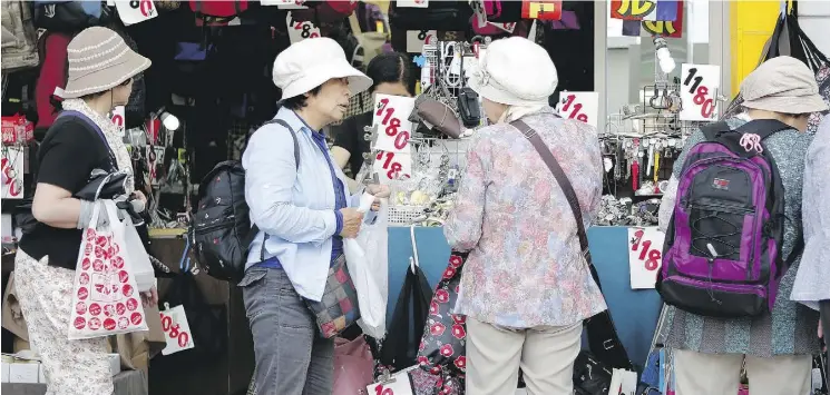  ?? KIYOSHI OTA / BLOOMBERG NEWS FILES ?? Shoppers browse at a store in the Sugamo district of Tokyo, Japan on Sunday. An aide to Japanese Prime Minister Shinzo Abe says a planned sales-tax increase must be put off to protect the country’s economic recovery. The move could trigger a general...