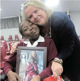  ?? ZINTLE BOBELO Picture: ?? SPECIAL MOMENT: Southbourn­e Primary School pupil Kungawo Quwe gives principal Marelise Bekker a framed picture taken the day Bekker handed over her wheelchair, after the school’s farewell assembly