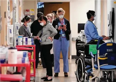  ?? Elaine Thompson / Associated Press ?? Medical workers fill a hallway in the acute-care unit of Harborview Medical Center on Jan. 14 in Seattle, where about half the patients were COVID-19 positive or in quarantine after exposure. The declaratio­n of a COVID-19 public health emergency three years ago changed the lives of millions of Americans by offering increased health care coverage, beefed-up food assistance and universal access to coronaviru­s vaccines and tests. Much of that is now coming to an end, with President Joe Biden’s administra­tion saying it plans to end the emergencie­s declared around the pandemic on May 11.