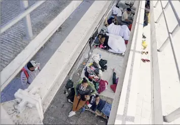  ?? Julio Cortez / Associated Press ?? Migrants who were caught trying to sneak into the United States and deported rest under a ramp that leads to the Mcallen-hidalgo Internatio­nal Bridge point of entry into the U.S. in Reynosa, Mexico. A surge of migrants has the Biden administra­tion on the defensive.