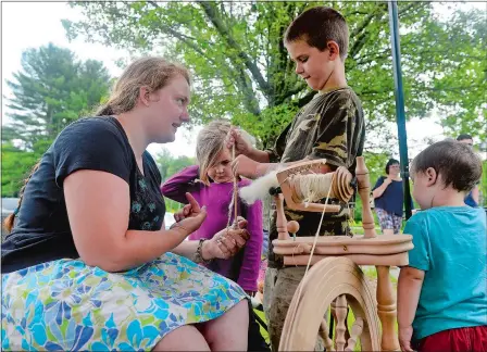  ?? SARAH GORDON/THE DAY ?? Sharon Finlayson, left, of Uncasville shows Liam Kelly, 8, of Ledyard how to use a drop spindle to spin yarn as his siblings Maeve, 5, and Aidan, 2, look on during a Maker Day event on Saturday at the Bill Library in Ledyard. The first-ever event...