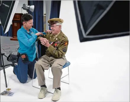  ?? SARAH GORDON/THE DAY ?? Photograph­er Stacy Pearsall adjusts the pose of WWII Army veteran Ben Cooper, of West Hartford, before she takes his portrait during a stop Monday of the Veterans Photo Project at the Submarine Force Library and Museum in Groton.