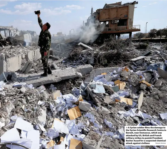  ?? Hassan Ammar ?? > A Syrian soldier films the damage to the Syrian Scientific Research Centre in Barzeh, near Damascus, which was attacked by US, British and French military strikes to punish President Bashar Assad for a suspected chemical attack against civilians