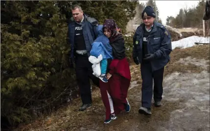  ?? DREW ANGERER, GETTY IMAGES ?? A mother and child from Turkey are escorted by Royal Canadian Mounted Police after crossing into Canada Thursday in Hemmingfor­d, Que.