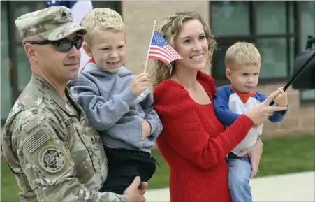  ?? Bill Uhrich — MeDianeWS groUP ?? army Sgt. 1st class Michael landeck celebrates his homecoming with his family friday, Sept. 30, during a surprise reunion at a pep rally at owatin creek elementary School in exeter township. landeck is holding son caleb, a first-grader, while his wife, Samantha Deshong, holds their son emmett, 2.