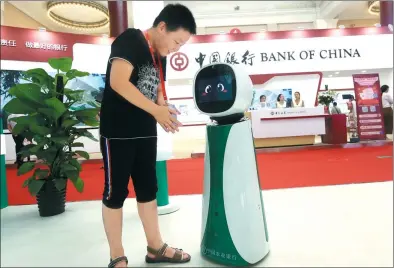  ?? LEI KESI / FOR CHINA DAILY ?? A boy interacts with a robot from Agricultur­al Bank of China at the 25th China Internatio­nal Finance Exhibition in Beijing on July 28.