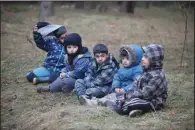  ?? (AP/BelTA/Leonid Shcheglov) ?? Children of migrants sit on the ground Friday as others from the Middle East and elsewhere gather at the Belarus-Poland border near Grodno, Belarus.