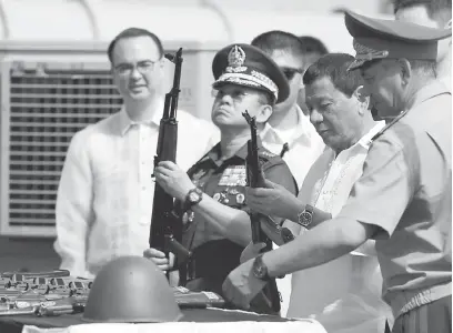  ?? — Gambar AFP ?? TERIMALAH: Duterte (dua kanan) dan Ano (dua kiri) memeriksa raifal Kalashniko­v sambil diperhatik­an Shoigu (kanan) semasa upacara penyerahan di Pelabuhan Manila semalam.