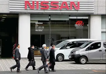  ?? — Reuters ?? Tough time: People walk past a dealer shop of Nissan in Tokyo. The automaker warned last month it expects to post a loss for the latest fiscal year through March.