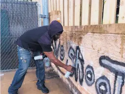  ?? JULIET LINDERMAN/ASSOCIATED PRESS ?? Tyree Colion spray paints the words “No Shoot Zone” on a wall behind a convenienc­e store near where a girl was fatally shot in Baltimore County, Md.