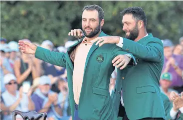  ?? REUTERS ?? Scottie Scheffler is presented with the green jacket by Jon Rahm after winning The Masters.