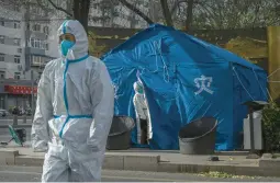  ?? KEVIN FRAYER/GETTY ?? Workers on Tuesday in Beijing wear personal protective gear to ward off COVID-19. Police in Beijing and several other Chinese cities are working to quell protests.