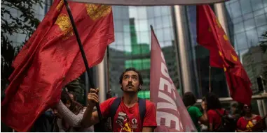  ??  ?? Sabrina Valle and Peter Millard Demonstrat­ors in Rio wave flags during a protest in solidarity with Petrobras oil workers