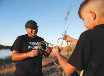  ??  ?? Randy Morin makes a hoop for a dream catcher with his nine-yearold son, Keesik, at Gabriel Dumont Park. Morin is a passionate advocate for his language and culture and speaks to his children in Cree.