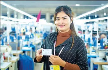  ?? OXFAM ?? A garment worker displays her NSSF card.