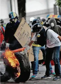  ?? Ueslei Marcelino/Reuters ?? Manifestan­te queima pneu em rua da capital Caracas; estatais e serviços públicos funcionara­m