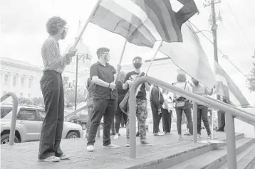  ?? JAKE CRANDALL/THE MONTGOMERY ADVERTISER ?? Demonstrat­ors backing transgende­r rights hold flags last month at the Alabama State House in Montgomery. Five states have moved to limit transgende­r youths’ ability to get certain medical treatment.