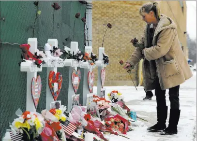  ?? Nam Y. Huh The Associated Press ?? A woman places flowers at a makeshift memorial Sunday in Aurora, Ill., near Henry Pratt Co. manufactur­ing company, where five people were killed in a shooting on Friday.