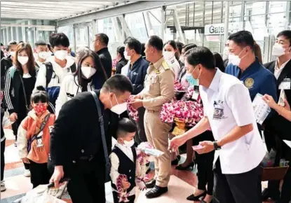  ?? YANG WANLI / CHINA DAILY ?? Thares Krasanaira­wiwong, director-general of the Disease Control Department with Thailand’s Ministry of Public Health, presents gifts to a Chinese boy and his father upon their arrival at Bangkok’s Suvarnabhu­mi Airport on Jan 9.