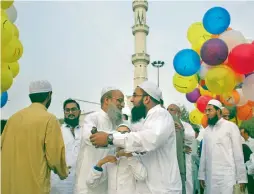  ?? Reuters, AP ?? Women pray after offering Eid Al Fitr prayers the Badshahi mosque in Lahore on Monday; and, right, men greet each other after the Eid prayers in Karachi. —