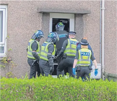  ?? Picture: Steven Brown. ?? Police officers force entry to a property in Kirkcaldy during a drug raid.