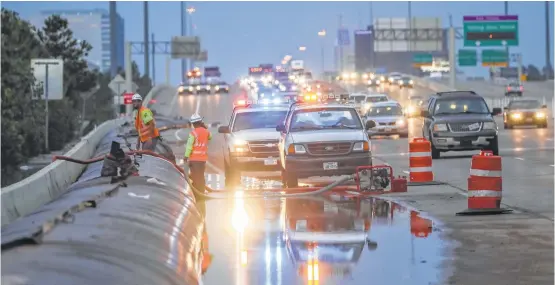  ?? Jon Shapley / Houston Chronicle ?? TXDOT workers construct a temporary dam on I-10 to stop water from the Addicks Reservoir from moving across the highway on Wednesday.