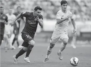  ?? — AFP ?? Barcelona’s Lionel Messi ( left) vies with Villarreal’s Manuel Trigueros Munoz during their La Liga match at the Camp El Madrigal Stadium in Villarreal on Sunday. Barcelona won 1- 0.