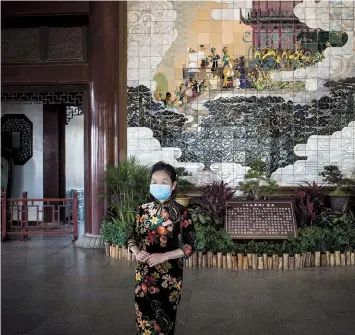  ??  ?? A visitor poses in the Yellow Crane Tower with her mask on. Strict anti-infection measures are still in force at public places in Wuhan.