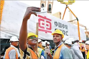  ?? SUN RUIBO / XINHUA ?? Workers take a selfie at a locomotive delivery ceremony in Mombasa, Kenya. The eight China-made locomotive­s will be used on the Mombasa-Nairobi railway.