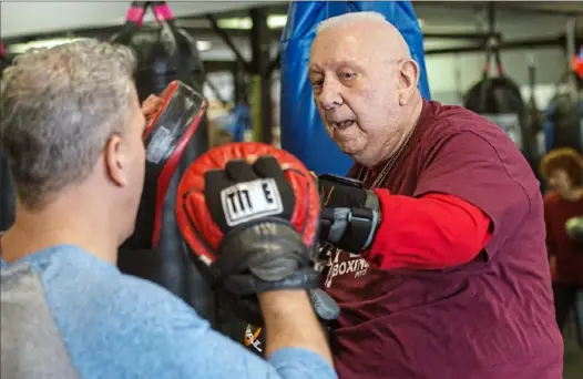  ?? Lake Fong/Post-Gazette photos ?? Above: Jimmy Hughes, 76, of Economy, practices punches with Rich Mushinsky, owner of Fit 4 Boxing Club, at a boxing class in December. Mr. Hughes, a retired police detective who has Parkinson’s, says the workouts help lessen the effects of the disease.